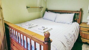 Un dormitorio con una cama de madera, una mesita de noche y una lámpara de pared.
