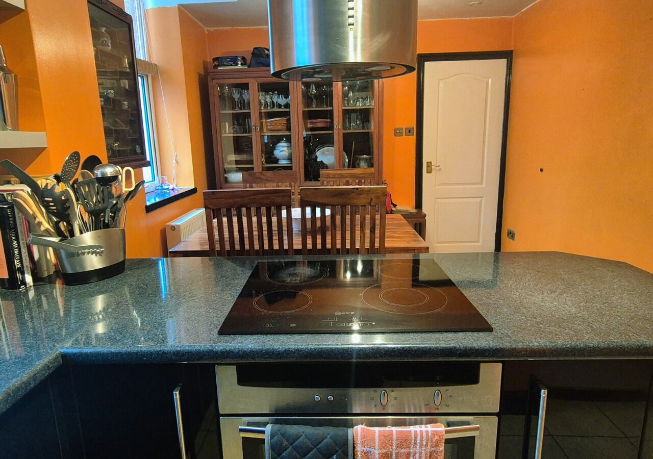 A kitchen with a built-in stove, oven, and a wooden dining table with chairs.