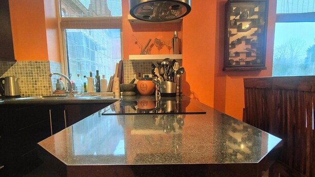 Una cocina con encimera de granito, un fregadero y diversos utensilios de cocina.