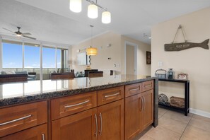A kitchen with granite countertops, wooden cabinets, and a view of the ocean. - Ocean Club.  Gulf Views.  Pool.  Walk to Beach (Biloxi)