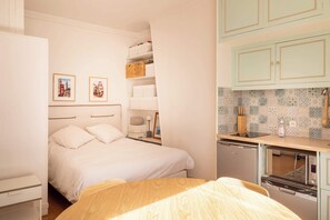 A bedroom with a bed, bedside tables, and a nightstand. There is a kitchenette with a microwave, toaster, and a small refrigerator. - Cozy Bright Studio for 2 Saint Germain des Pres (Paris)