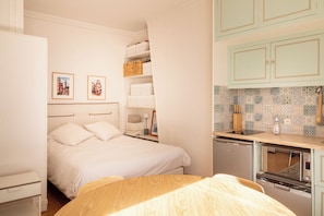 A bedroom with a bed, bedside tables, a wardrobe, and a kitchenette with a microwave and toaster. - Cozy Bright Studio for 2 Saint Germain des Pres (Paris)