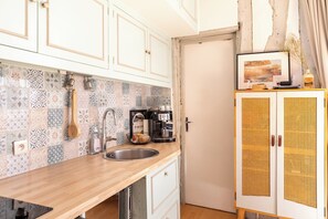 Eine Küche mit gefliestem Fliesenspiegel, einer Kaffeemaschine und einem Schrank mit Lochmusterdesign.