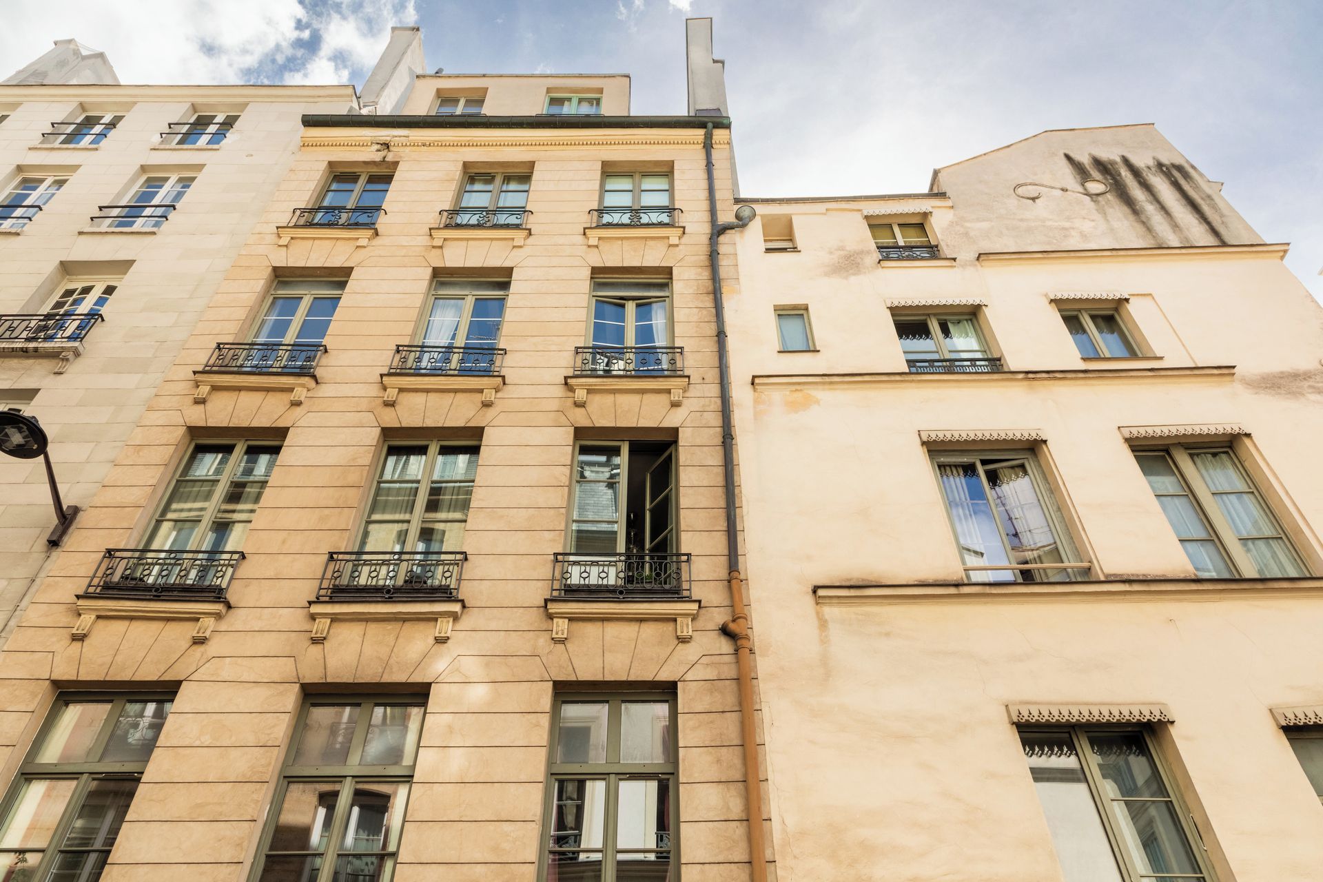 Un immeuble à plusieurs étages, de style architectural classique, doté de balcons avec des garde-corps en métal et de grandes fenêtres.