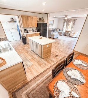 A modern kitchen with wooden cabinets, a central island, and a dining area with a table set for two.