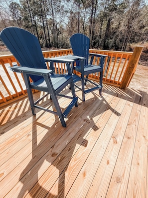 A deck with two blue Adirondack chairs and a small table.