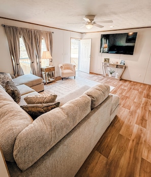 A living room with a sofa, armchairs, a TV, and a ceiling fan.