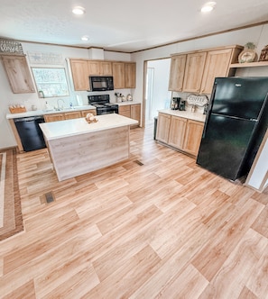 A modern kitchen with wooden cabinets, a black refrigerator, and a central island.