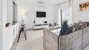 Un soggiorno moderno con una TV a schermo piatto, un divano, un tavolino da caffè e un'area pranzo con tavolo e sedie.