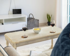 A living room with a wooden coffee table, two wine glasses, a bowl of butter, a white cabinet, and a potted plant. - The Studio - VALE DO LOBO (Vale do Lobo)