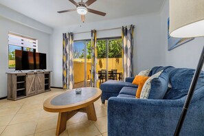 Ein Wohnzimmer mit Fernseher, Sofa und Deckenventilator.
