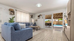 Uma sala de estar com sofá, mesa de centro e vista para uma piscina.
