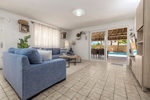 Ein Wohnzimmer mit einer Couch, einem Couchtisch und Blick auf einen Pool.