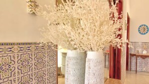 A hallway with patterned tiles, two tall white vases with intricate designs, and a decorative wall piece. - Room 'Quarto 1' with Shared Pool, Wi-Fi and Air Conditioning (Moncarapacho)