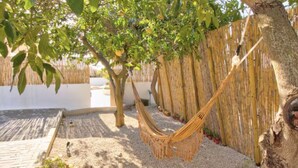 A hammock under a tree in a courtyard with a bamboo fence and potted plants. - Room 'Quarto 1' with Shared Pool, Wi-Fi and Air Conditioning (Moncarapacho)