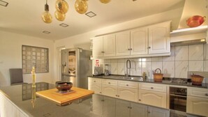 A modern kitchen with white cabinets, a granite countertop, and a built-in oven. - Room 'Quarto 2' with Shared Pool, Shared Terrace and Wi-Fi (Moncarapacho)