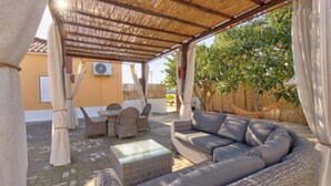 A covered outdoor seating area with wicker furniture, a table, and a hammock. - Room 'Quarto 2' with Shared Pool, Shared Terrace and Wi-Fi (Moncarapacho)