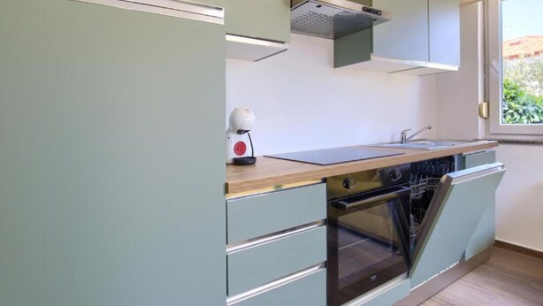 Eine kompakte Küche mit Backofen, kleiner Spüle und Fenster für natürliches Licht.