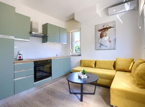 A modern kitchen with a built-in oven, a dining table, and a yellow sofa. - One Bedroom Apartment With Terrace (Pula)