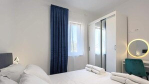 Ein Hotelzimmer mit Bett, Schreibtisch, Stuhl, Spiegel und einem Fenster mit Vorhängen.