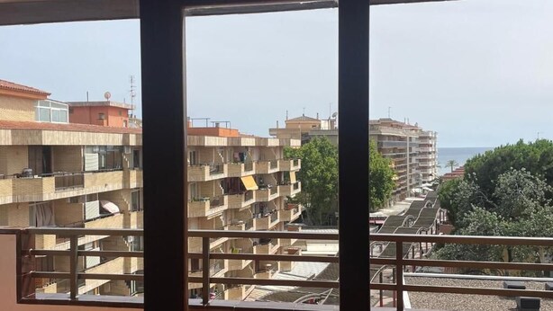 Varanda com vista para edifícios altos e uma costa distante.