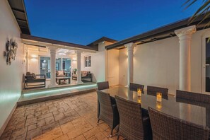Eine Terrasse im Freien mit Esstisch und Stühlen, einem überdachten Sitzbereich und Blick auf den Himmel.