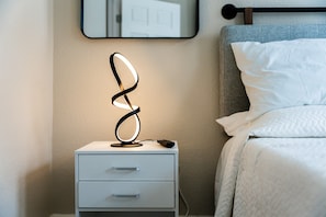 Ein Nachttisch mit moderner Lampe, einer Schublade und einer Fernbedienung.
