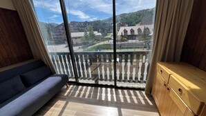 A room with a large window, a wooden floor, a sofa, and a wooden cabinet. - 4 bed apartment - La Joue du Loup (Dévoluy)
