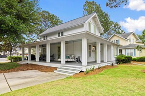 A two-story house with a covered porch, a front yard, and a driveway. - NEW to VRBO -HUGE PORCH~Golf Cart, FREE GOLF~HEATED Pool* & HotTub, Gym (Miramar Beach)