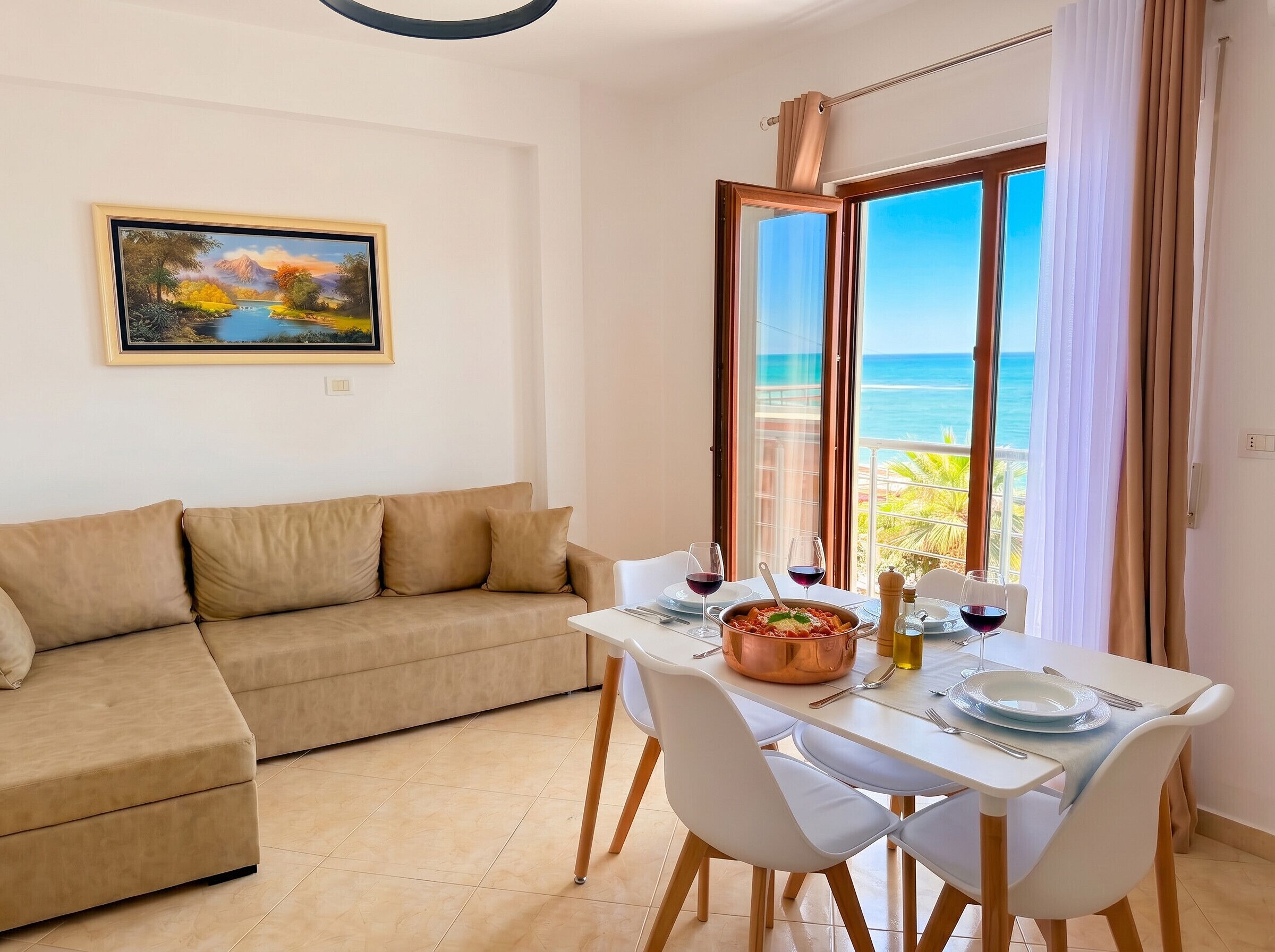 Ein Zimmer mit einer Couch, einem Esstisch, Stühlen, einem Gemälde und Meerblick.