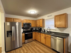 A modern kitchen with wooden cabinets, stainless steel appliances, and a black countertop. - “Stylish 3BR Near NoDa w/ Outdoor Lounge" (Charlotte)