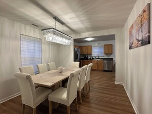 A dining area with a wooden table and chairs, a chandelier, and a kitchen in the background. - “Stylish 3BR Near NoDa w/ Outdoor Lounge" (Charlotte)