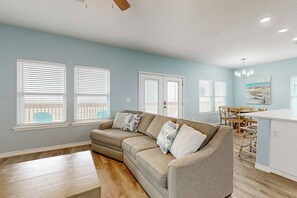 Ein Wohnzimmer mit einem beigen Sofa, ein Essbereich mit Holzstühlen und eine Kücheninsel.