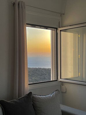 A room with a view of the sea at sunset, a window with curtains, and a sofa with cushions. - Eagle s Nest Kythnos (Kithnos)