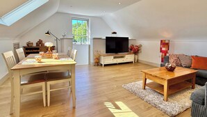 A spacious living area with a dining table, chairs, a sofa, a coffee table, a TV, and a large window. - Charming Barn Annex With Stables New Forest Escape (Ringwood)