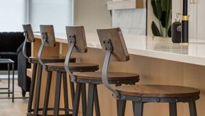 A bar area with wooden stools and metal frames, a counter, and a plant in the background. - Chic Retreat 4 BR Near UofC & HWY , Free Parking (Calgary)
