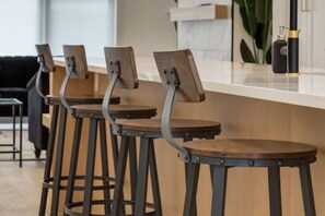 A bar area with wooden stools and metal frames, a counter, and a plant in the background. - Chic Retreat 4 BR Near UofC & HWY , Free Parking (Calgary)