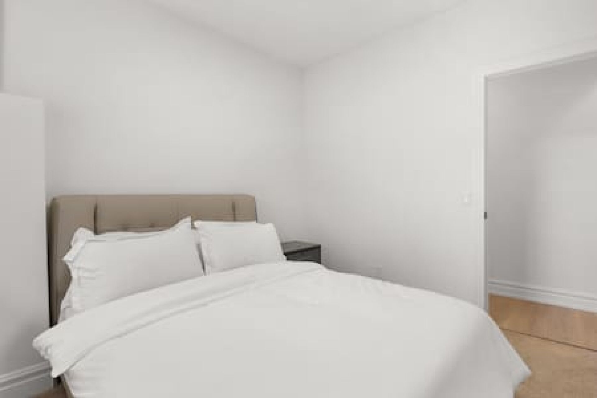 A bedroom with a bed, a nightstand, and a door.