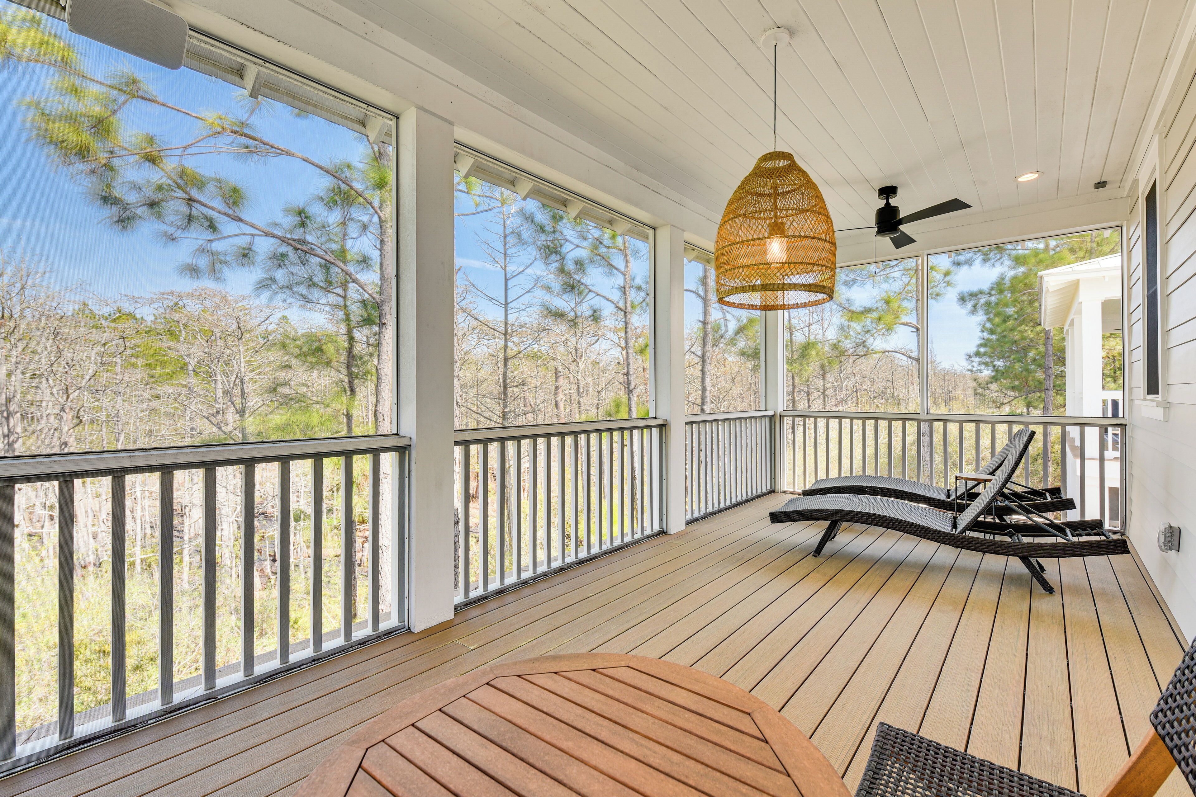 A wooden deck with a table and chairs, a hanging light fixture, and a ceiling fan.