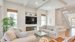 A spacious living room with a large flat-screen TV, two sofas, a coffee table, and a staircase leading to another level. - Elegant Santa Rosa Beach House w/ Community Perks (Santa Rosa Beach)
