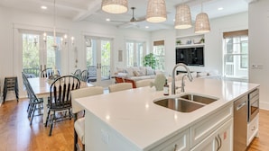 A spacious kitchen with a large island, white countertops, and a built-in oven. There are pendant lights above the island, and the room has large windows. - Elegant Santa Rosa Beach House w/ Community Perks (Santa Rosa Beach)