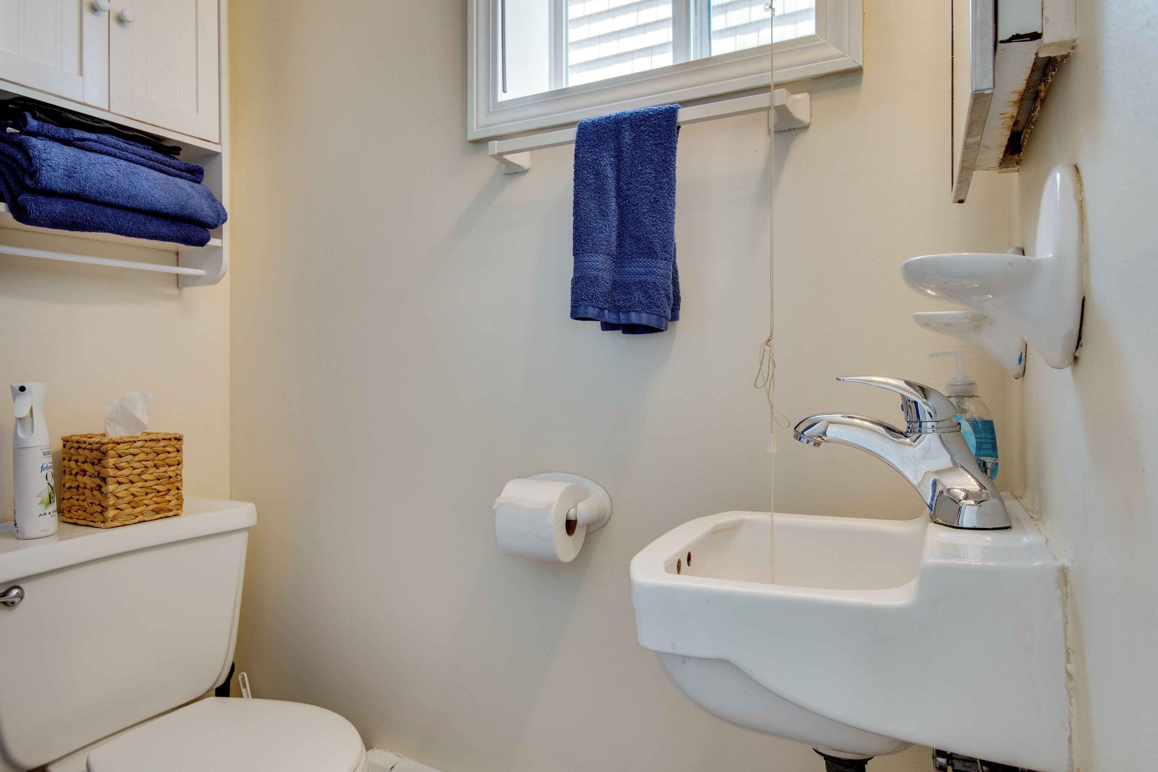 A bathroom with a toilet, a sink, a window, and a towel rack.