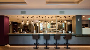 A bar area with a counter, multiple stools, and hanging spherical light fixtures. - Premier Inn Frankfurt Eschborn (Eschborn)
