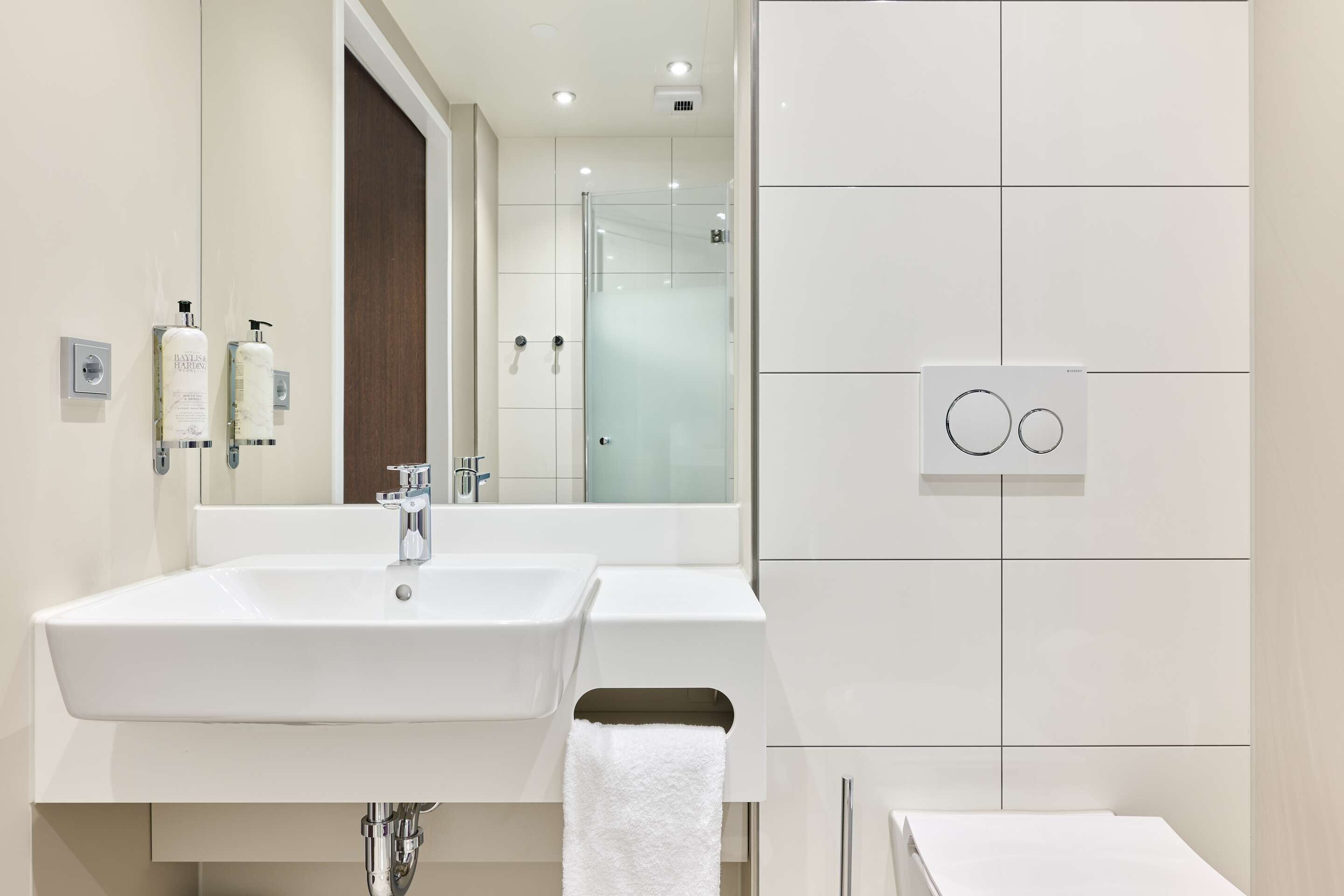 A modern bathroom with a large sink, mirror, and glass shower enclosure.