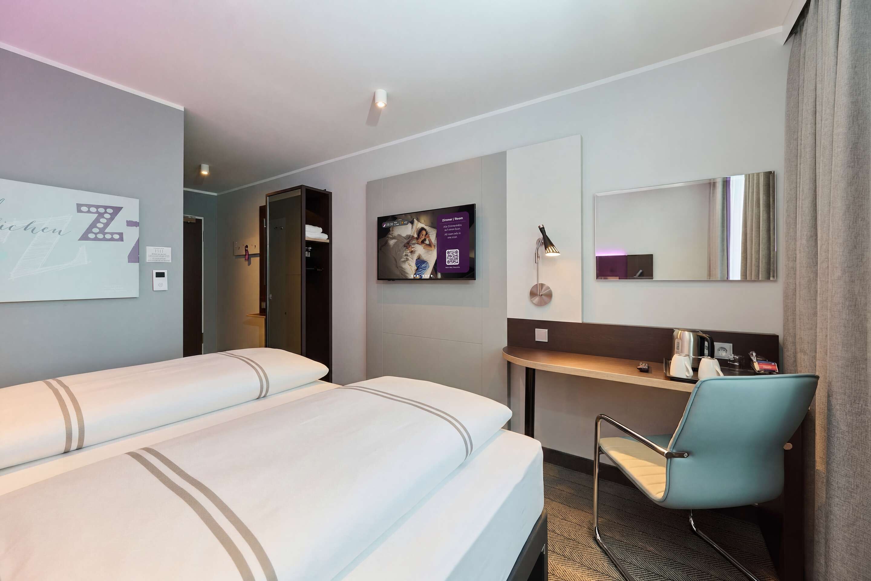 Une chambre d’hôtel avec deux lits, un bureau, une chaise, une télévision et un miroir.
