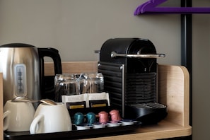 A coffee station with a coffee maker, a kettle, and a tray with coffee pods and a mug. - Premier Inn Frankfurt Eschborn (Eschborn)