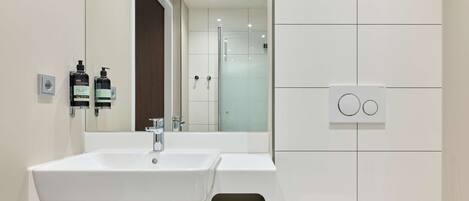 A modern bathroom with a double sink, a mirror, and a towel rack.