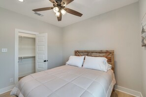 A bedroom with a bed, a wooden headboard, a ceiling fan, and a door leading to a closet.