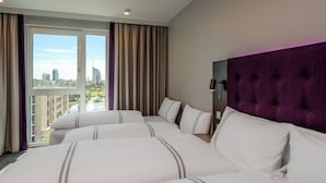 A hotel room with a large bed, a purple headboard, and a city view.