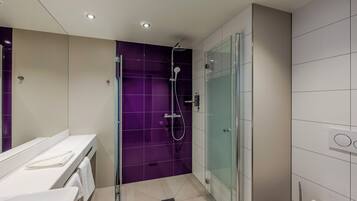 A modern bathroom with a glass shower enclosure, a white sink, and a mirror.